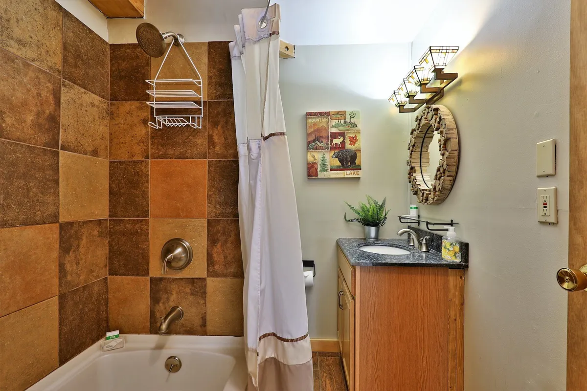 A tranquil bathroom scene featuring a bathtub, a stylish vanity with sink, decorative mirror, and wall art. The serene atmosphere suggests a space ideal for unwinding and self-care after a day of adventure.